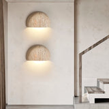 "Pair of travertine wall lamps illuminating a modern hallway and staircase with a soft, downward glow."