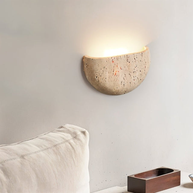 "A minimalist, semi-circular travertine wall lamp providing soft, downward lighting in a modern living room."