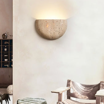 "A semi-circular travertine wall lamp with organic patterns emitting a soft glow in a modern living room."