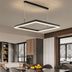 Modern black square LED pendant light suspended above a contemporary kitchen dining area with marble countertops.