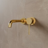 Close-up of Vartay Bathroom Faucet in polished gold, wall mounted with a sleek round handle and curved spout.