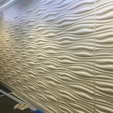 Vefni Panels - Durable, Modern Design for Any Space. White 3D PVC wall panels with flowing wave design installed in a hallway setting.