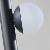 "Close-up of a glowing orb accent on a sleek, iron and acrylic pendant light with cylindrical rods."