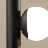 "Close-up of a glowing orb accent on a sleek, iron and acrylic pendant light with a cylindrical rod."