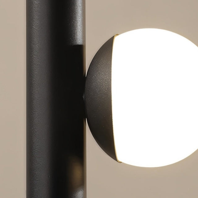 "Close-up of a glowing orb accent on a sleek, iron and acrylic pendant light with a cylindrical rod."