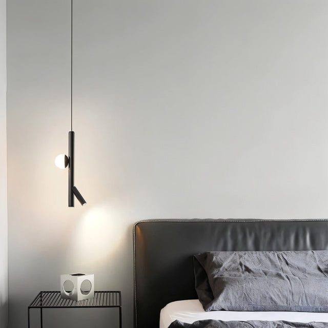  "A sleek, iron and acrylic pendant light with cylindrical rods and a glowing orb accent hangs in a modern bedroom at night, casting light on a side table and bed."