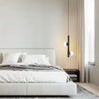 "A modern bedroom featuring a sleek iron and acrylic pendant light with cylindrical rods and glowing orb accents hanging above a platform bed."