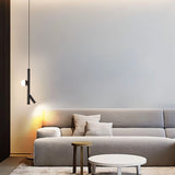 "A modern living room featuring a sleek iron and acrylic pendant light with cylindrical rods and a glowing orb accent, hanging above a gray sofa."