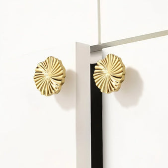 "Two gold brass fan-shaped drawer pulls mounted on white cabinet doors."