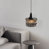 "A pendant light with a rippled glass shade beside a bedroom side table."