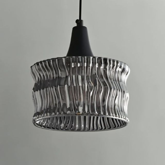 "A pendant light with a rippled glass shade and black cord."