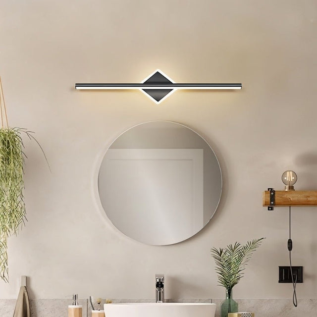 "A modern black wall lamp with a diamond-shaped base and horizontal bar, mounted above a round mirror in a contemporary bathroom."
