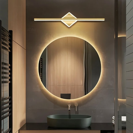 "A modern gold wall lamp with a diamond-shaped base and horizontal bar, mounted above a round mirror with integrated lighting in a contemporary bathroom."