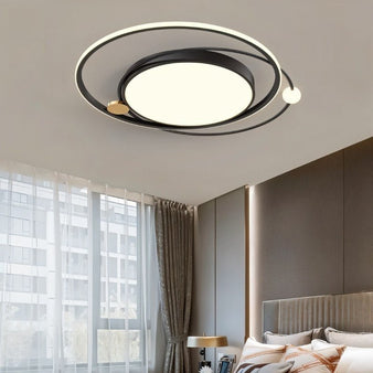 "A black LED ring ceiling light with intertwined rings in a bedroom."