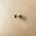 Gold ribbed cabinet pulls with sphere finials on textured beige surface with pearls and fabric.