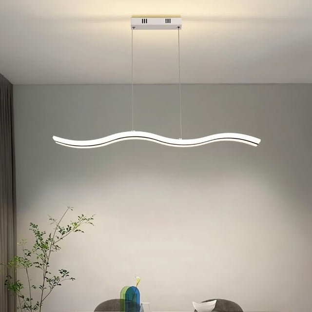 "A modern LED pendant light with an undulating wave design, illuminating a dining room with a plant and table setting."