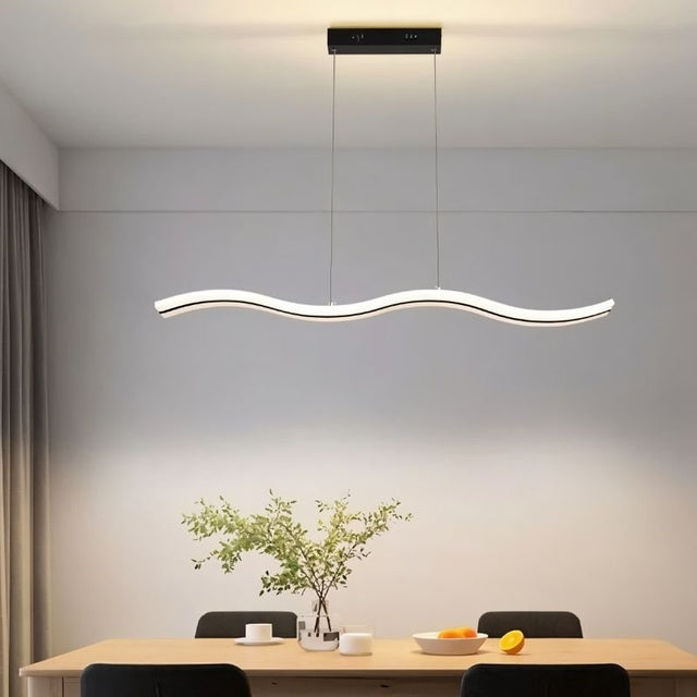 "A modern LED pendant light with an undulating wave design, illuminating a dining table with place settings and a plant."