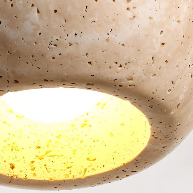 "Close-up detail of a travertine pendant light with a warm light glow."