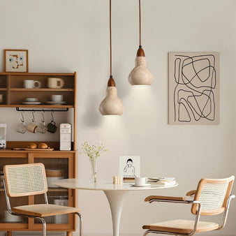 "Two travertine pendant lights hanging over a dining table in a dining room."