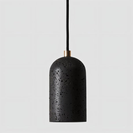"Modern cylindrical pendant light in black travertine with brass detailing, showcasing its natural, textured surface."