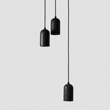 "Arrangement of modern cylindrical pendant lights crafted from black travertine, showcasing their natural, textured surface and contemporary design."