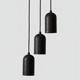 "Group of modern cylindrical pendant lights crafted from black travertine, showcasing their natural, textured surface and contemporary design."