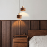 Vesil Copper & Wood Pendant Light Fixture hanging above a wooden nightstand in a modern bedroom with warm ambient lighting.