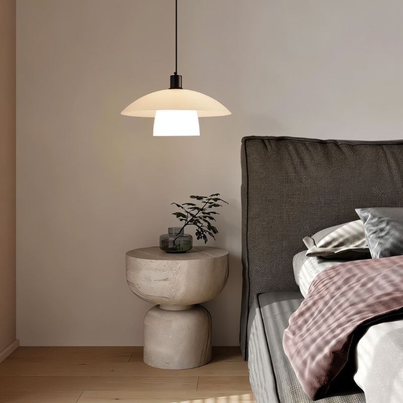 "A layered glass pendant light hanging beside a bed, providing soft ambient lighting in a modern bedroom."