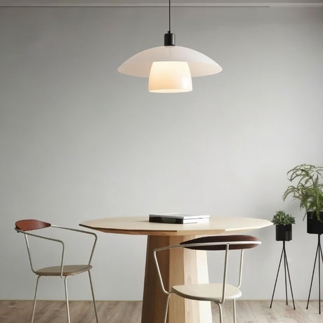 "A layered glass pendant light hanging above a round table with two chairs."