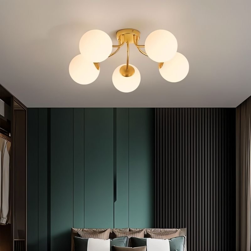 "A 5-light gold ceiling light with spherical glass shades in a bedroom."