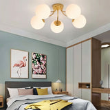 "A gold ceiling light with spherical glass shades in a modern bedroom."