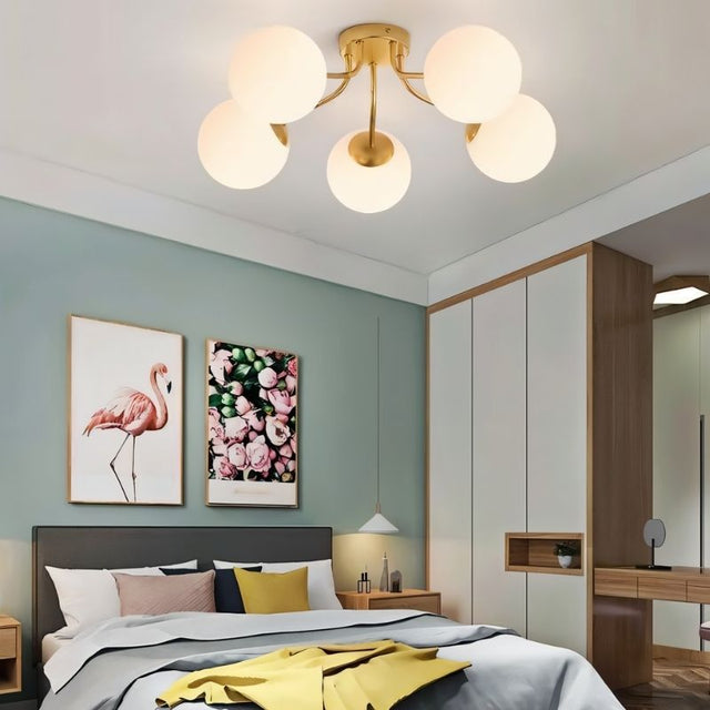 "A gold ceiling light with spherical glass shades in a modern bedroom."