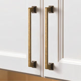 "Two vintage brass pull bars with a sleek, modern rectangular design, installed on white kitchen cabinets, offering a luxurious and functional touch."