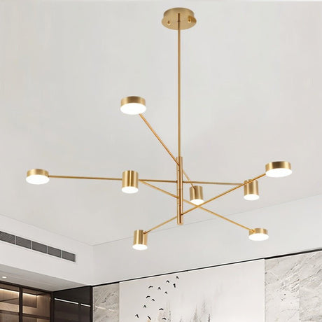 "A gold chandelier with multiple arms extending in different directions, each with a small, round light at the end, shown installed on a white ceiling above a minimalist artwork with black lines on a white background."