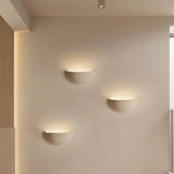 "Three sleek, minimalist, half-moon shaped trimless lights made of gypsum and metal, recessed into a hallway wall, providing a soft, ambient glow for modern interiors."