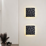 "Two black travertine wall lamps with hexagonal patterns, backlit glow, mounted on a wall in a modern interior."