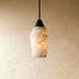 White marble pendant light with black metal fixture hanging above nightstand in modern bedroom setting.