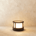Black modern wall sconce with geometric cube design mounted on white exterior wall at dusk with blue sky.