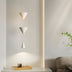 "Modern pendant light with stacked conical shades in a minimalist bedroom setting, providing a focused yet ambient glow."