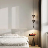 "Modern black pendant light with stacked conical shades illuminating a minimalist bedroom."