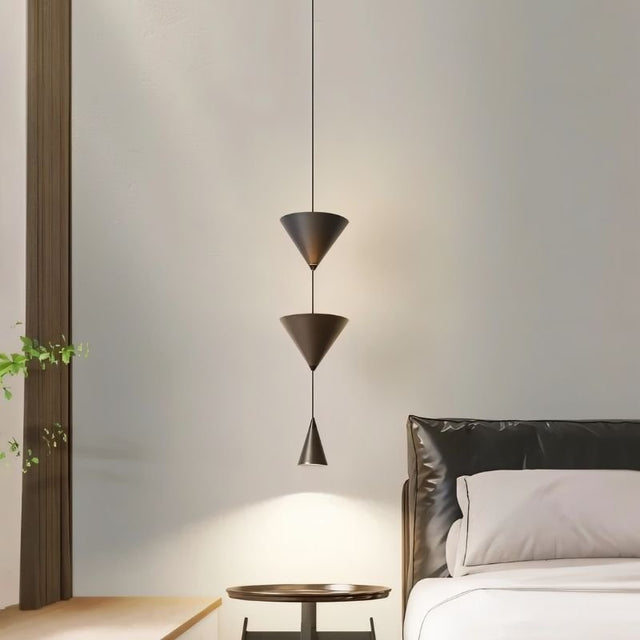"Modern pendant light with stacked conical shades creating a focused glow in a minimalist bedroom setting."