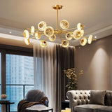 "A modern chandelier with circular glass accents and a gold metal frame in a living room with a city view."