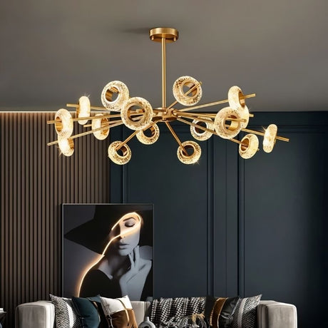 "A modern chandelier with circular glass accents and a gold metal frame hanging in a contemporary living room."