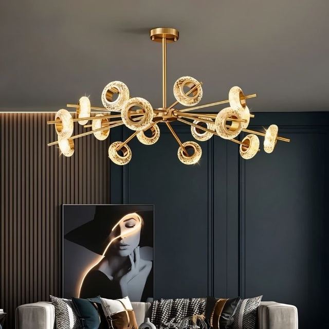 "A modern chandelier with circular glass accents and a gold metal frame hanging in a contemporary living room."
