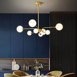 "A gold chandelier with eight frosted glass globes, hanging above a dining table in a room with a dark blue wall."