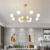 "A gold chandelier with multiple frosted glass globes, hanging above a living room sofa with artwork on the wall."