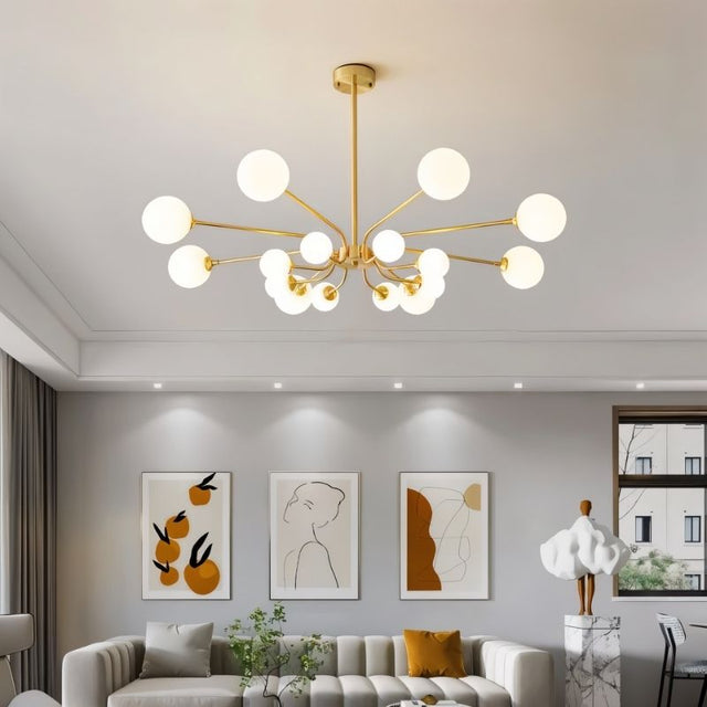 "A gold chandelier with multiple frosted glass globes, hanging above a living room sofa with artwork on the wall."