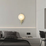 "Modern wall lamp with a round white glass shade and a vertical rod, illuminating a contemporary bedroom."