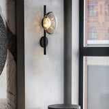 "Modern wall lamp with a smoked glass shade and a black rod, providing accent lighting in a contemporary living room."