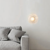 "Modern wall lamp with a clear glass shade illuminating a contemporary living room."